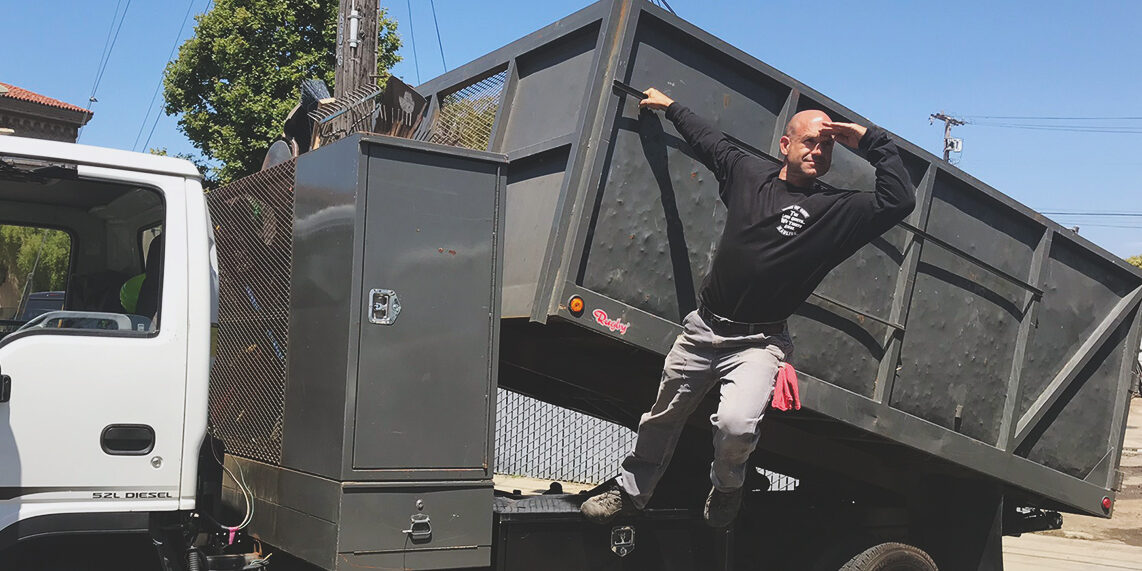 Dumpster Rental for Home Renovation by Sons of Odin Hauling Man loading debris into a dumpster for a home renovation project.
