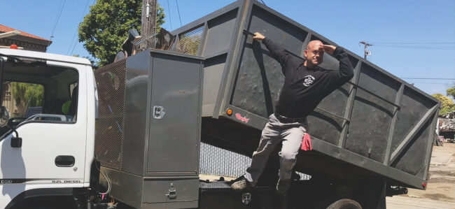 Man loading debris into a dumpster for a home renovation project.